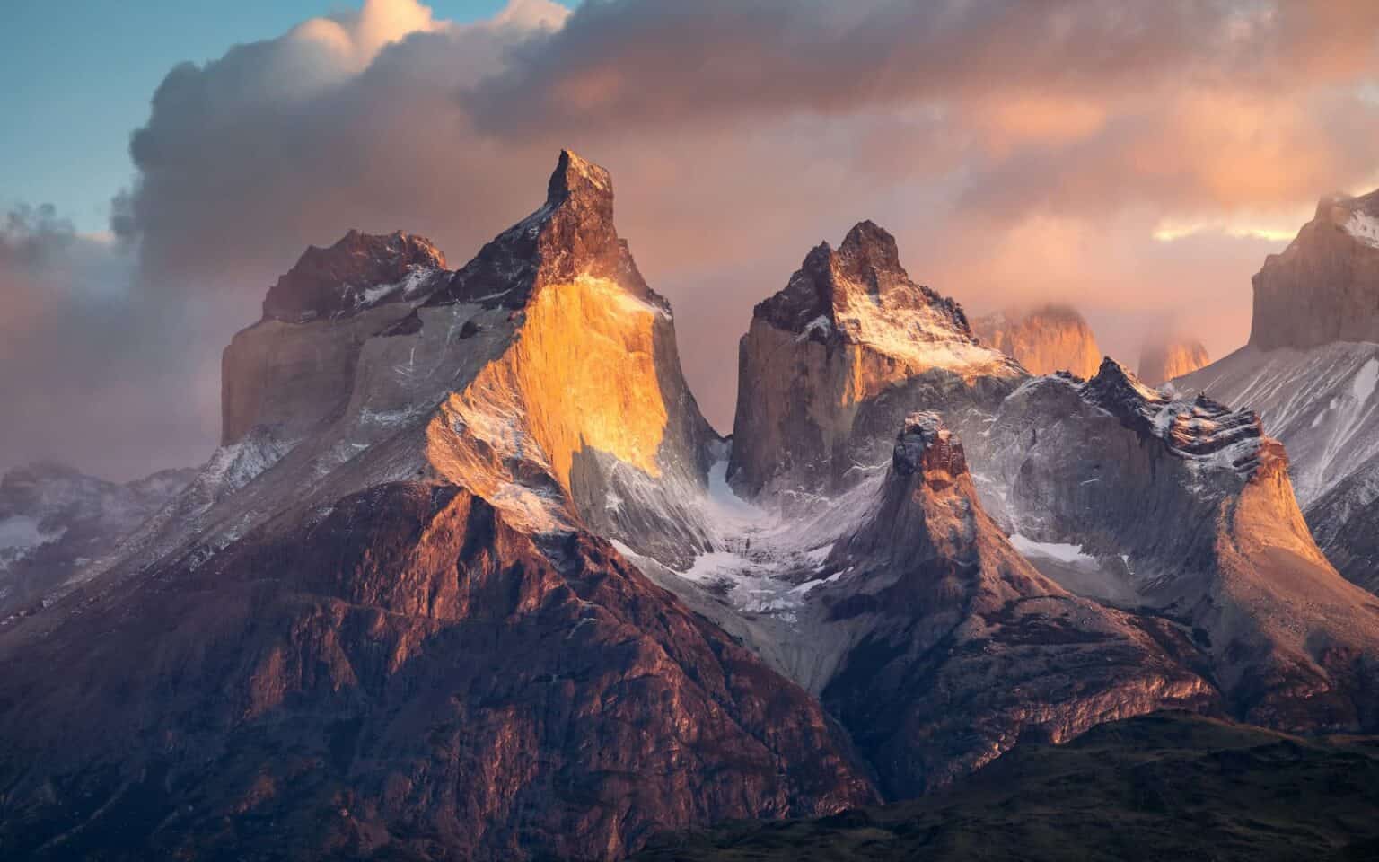 Beautiful shot mountains with clouds on the background and snows covering them